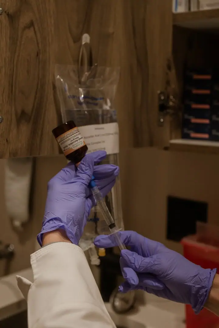 A healthcare professional preparing IV Hydration Therapy injection with gloves