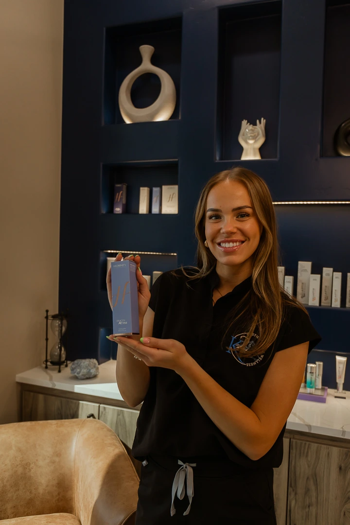 Smiling woman holding medical grade skin product in modern skincare clinic