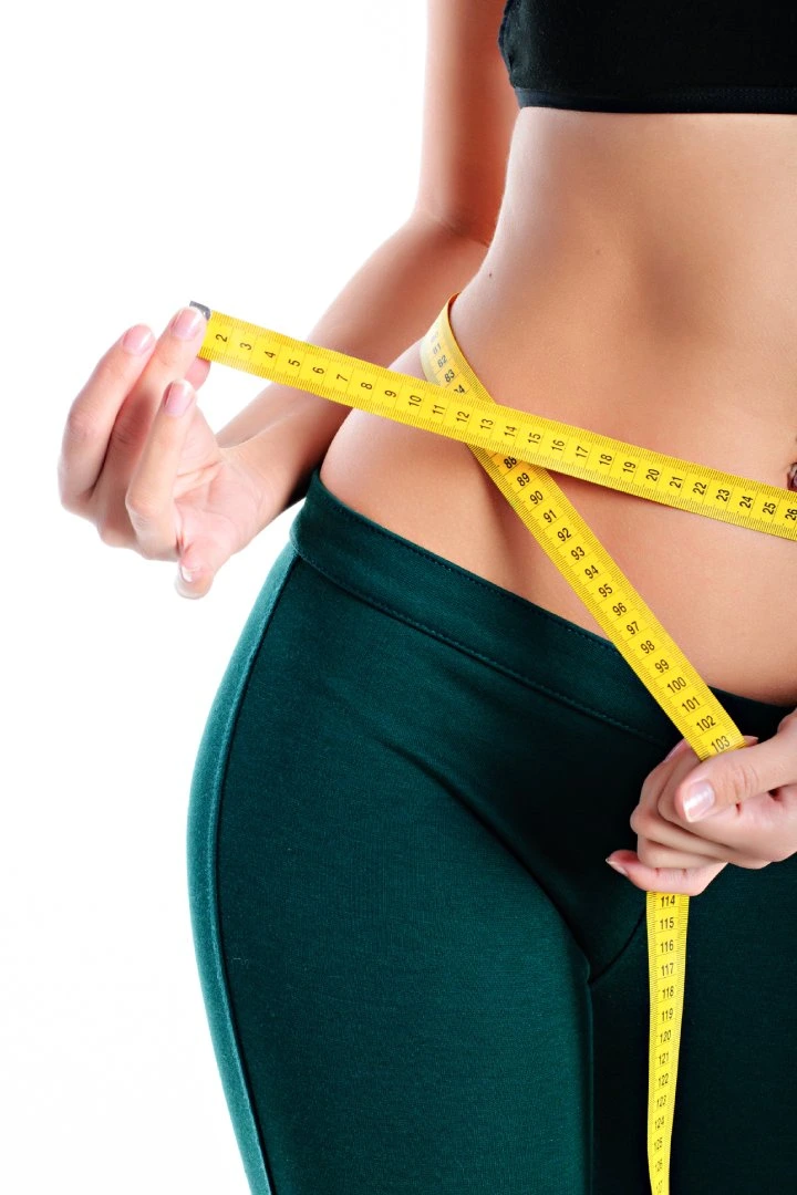 Woman measuring slim waist with tape for medical weight loss goals