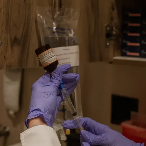 A healthcare professional preparing IV Hydration Therapy injection with gloves